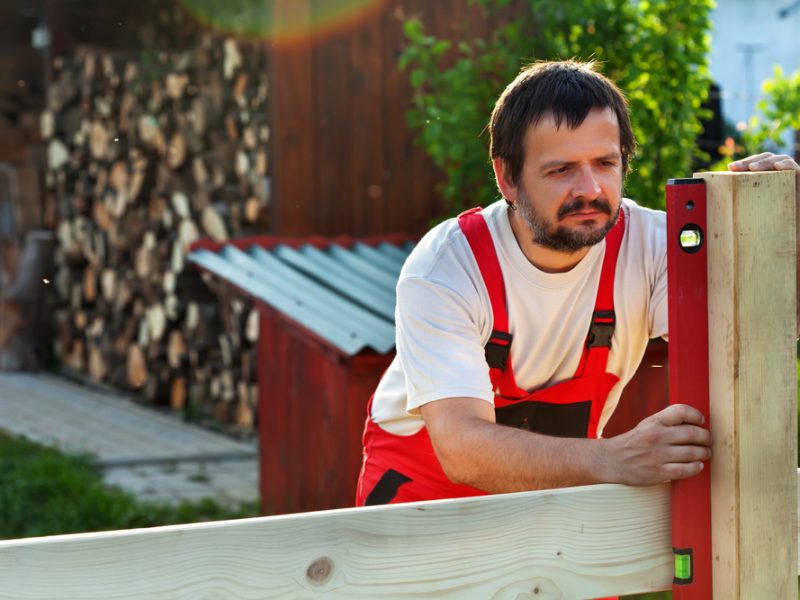 Man measuring up for building a picket fence