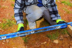 man with a spirit level measuring up for building a picket fence