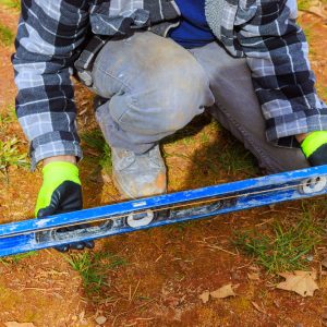man with a spirit level measuring up for building a picket fence