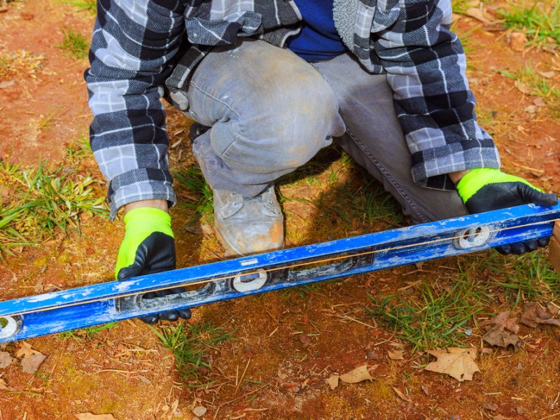 man with a spirit level measuring up for building a picket fence
